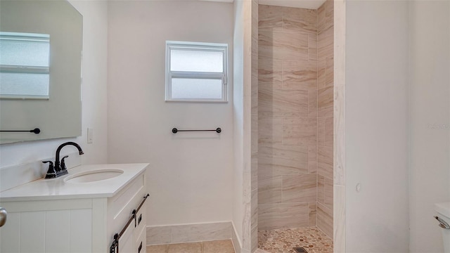 bathroom featuring tile patterned flooring, vanity, and a tile shower