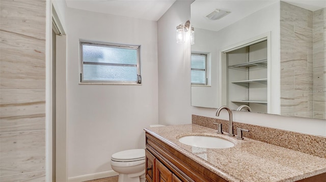 bathroom with a wealth of natural light, vanity, and toilet