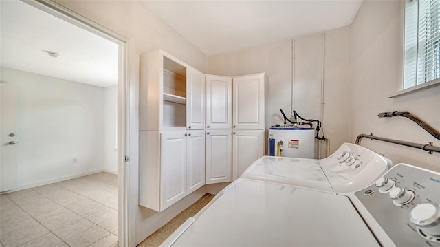 washroom featuring water heater, cabinets, washer and clothes dryer, and light tile patterned floors