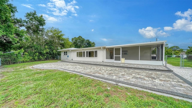 back of property with a sunroom, a yard, and a patio area