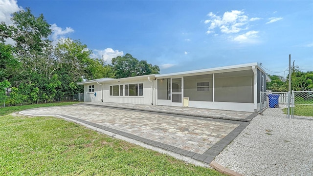 rear view of house featuring a patio area, a sunroom, and a yard