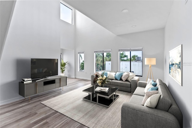 living room with a towering ceiling, baseboards, and wood finished floors