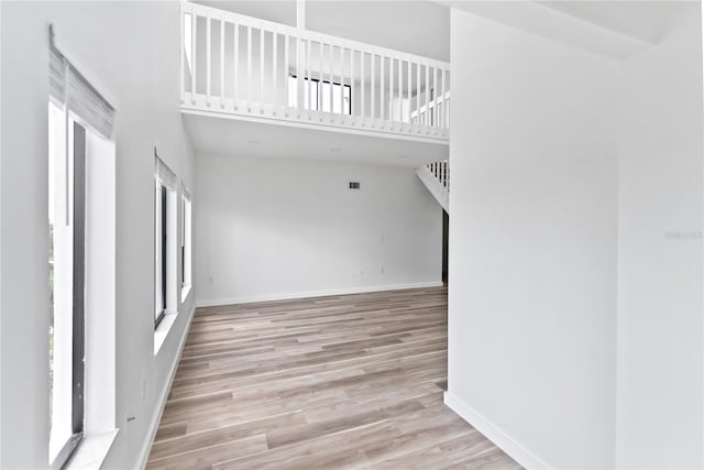 empty room featuring wood finished floors, a towering ceiling, and baseboards