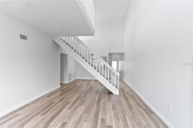 interior space with light wood-style flooring, stairs, visible vents, and baseboards