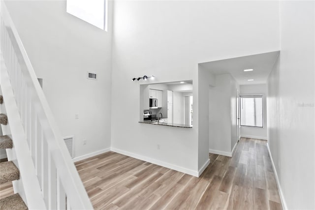 unfurnished living room featuring stairway, light wood-type flooring, and visible vents