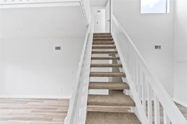 stairway with visible vents, baseboards, and wood finished floors