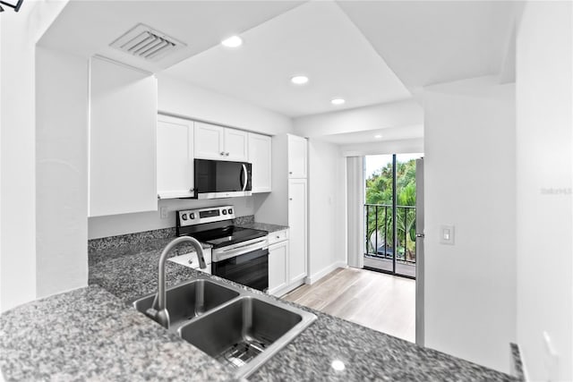 kitchen with stainless steel range with electric cooktop, a sink, visible vents, and white cabinetry