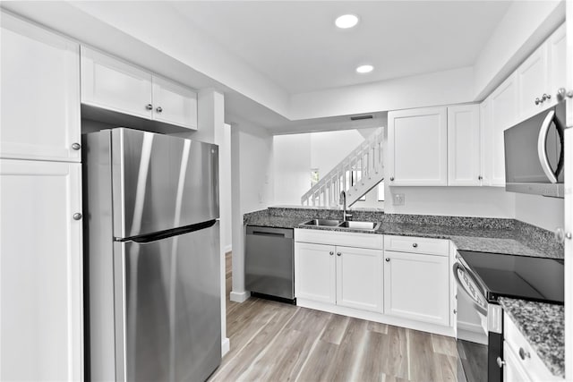 kitchen featuring stainless steel appliances, a sink, and white cabinetry