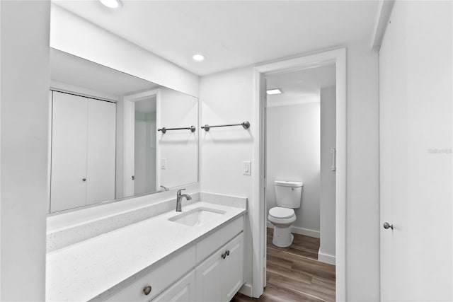 bathroom featuring toilet, recessed lighting, wood finished floors, vanity, and baseboards