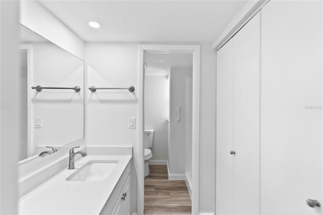 bathroom featuring baseboards, vanity, toilet, and wood finished floors