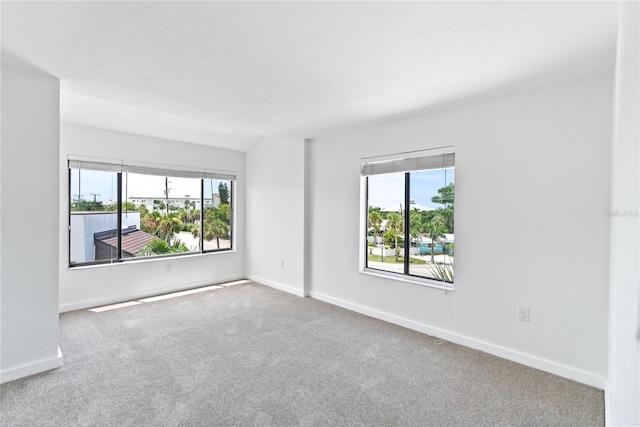 unfurnished room featuring plenty of natural light, carpet flooring, and baseboards