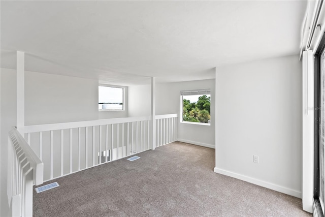 empty room with carpet flooring, visible vents, and baseboards