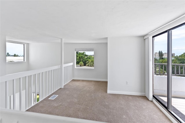 carpeted spare room featuring visible vents and baseboards