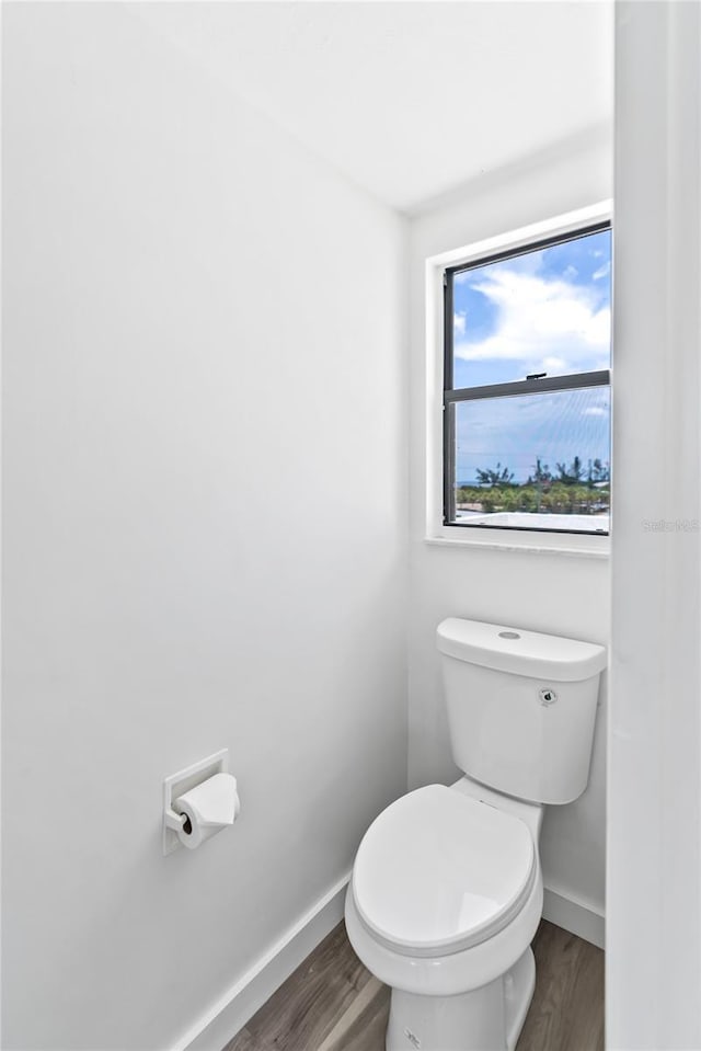 bathroom with toilet, baseboards, and wood finished floors