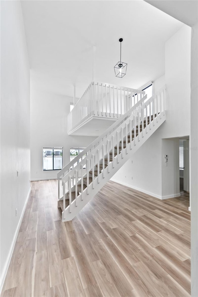 staircase with baseboards, a high ceiling, and wood finished floors