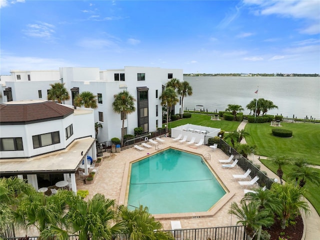 community pool featuring a water view, fence, and a patio