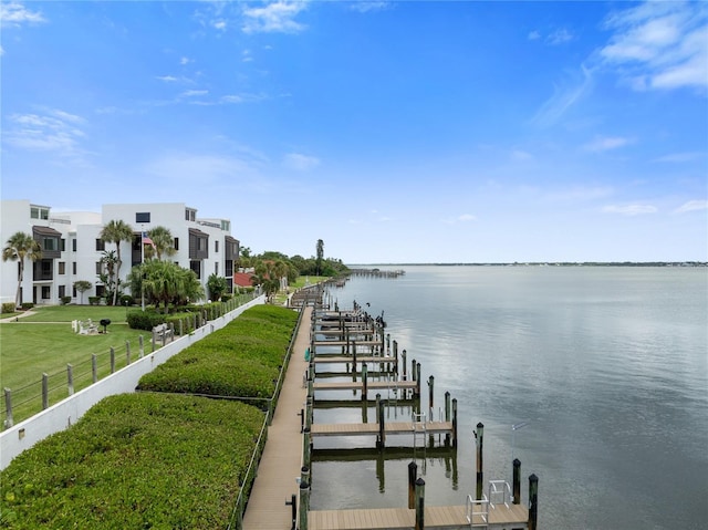 dock area with a yard, a water view, and fence