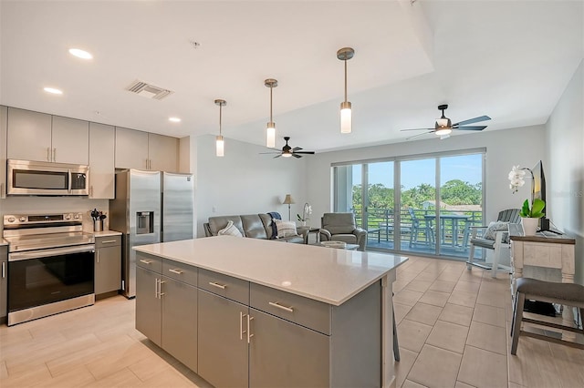 kitchen featuring gray cabinets, a center island, appliances with stainless steel finishes, and ceiling fan