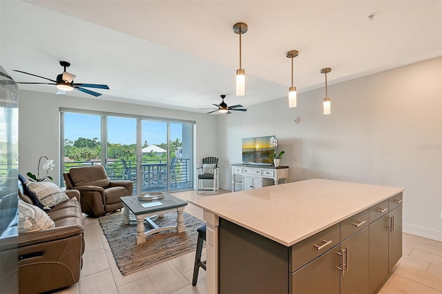 kitchen featuring ceiling fan, pendant lighting, a center island, a kitchen bar, and gray cabinetry