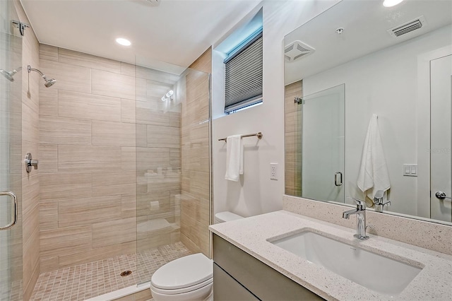 bathroom featuring vanity, walk in shower, and toilet