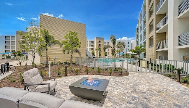 view of patio / terrace featuring a balcony, an outdoor living space with a fire pit, and a community pool