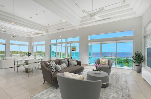 sunroom featuring a tray ceiling, a water view, and ceiling fan