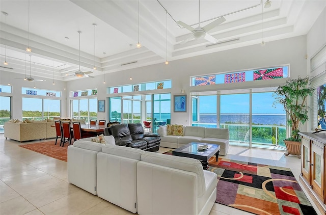 living room featuring a high ceiling, a water view, ceiling fan, and light tile patterned floors