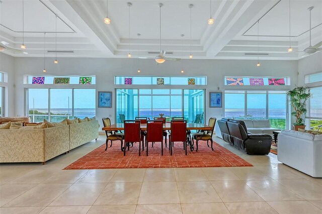 dining area with a wealth of natural light, light tile patterned floors, and a towering ceiling