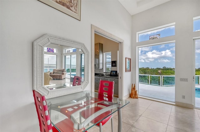 tiled dining room with a water view, a towering ceiling, and plenty of natural light