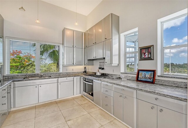 kitchen featuring stainless steel appliances, sink, pendant lighting, light tile patterned floors, and light stone countertops