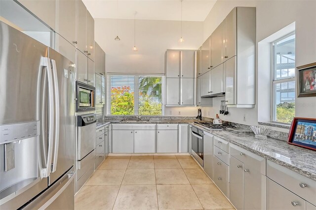 kitchen featuring sink, light tile patterned floors, light stone counters, and stainless steel appliances