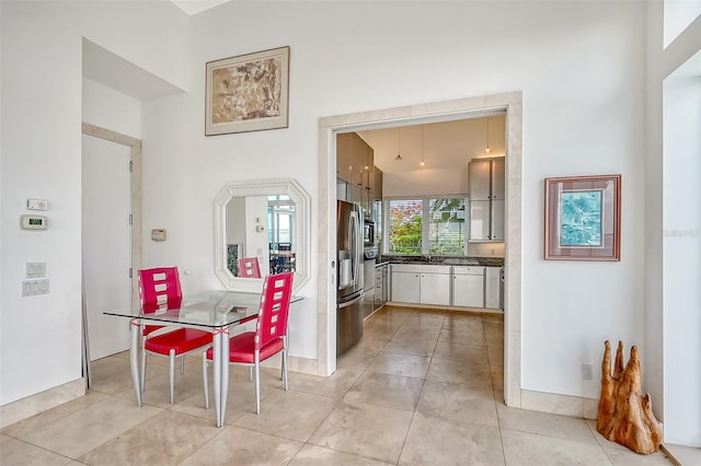 kitchen with stainless steel fridge with ice dispenser, white cabinetry, a towering ceiling, and light tile patterned floors