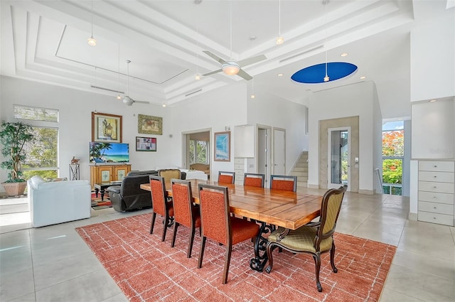 dining room featuring a high ceiling, a tray ceiling, ceiling fan, and light tile patterned floors