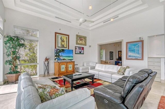 tiled living room featuring a high ceiling, ceiling fan, and a tray ceiling