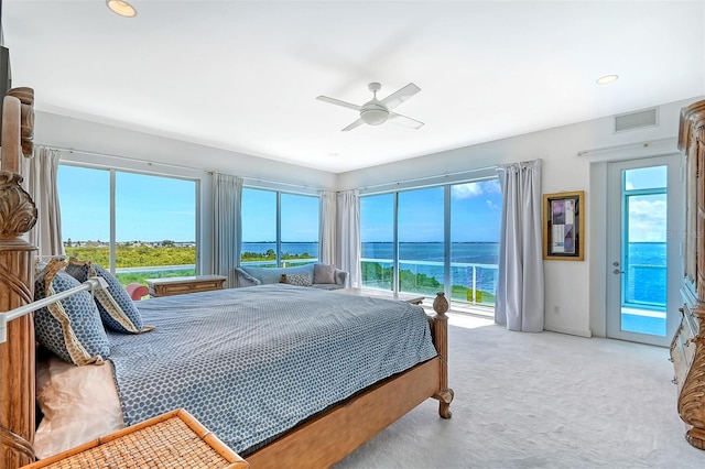 bedroom with carpet flooring, a water view, multiple windows, and ceiling fan