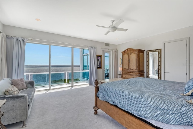 carpeted bedroom with access to outside, ceiling fan, and a water view