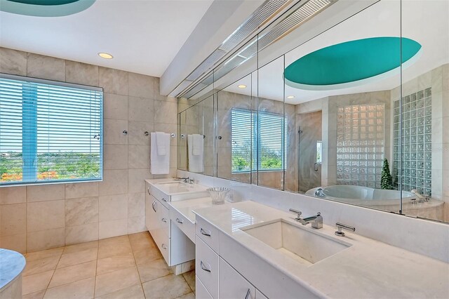 bathroom with independent shower and bath, tile walls, tile patterned floors, and double sink vanity