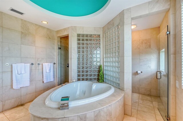 bathroom featuring plus walk in shower, tile walls, and tile patterned floors