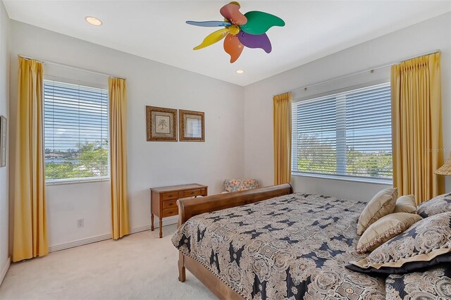 bedroom featuring light carpet, multiple windows, and ceiling fan