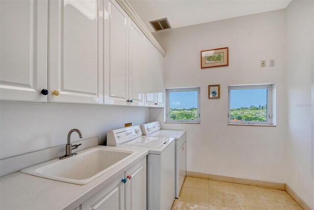 laundry area with light tile patterned flooring, sink, cabinets, and independent washer and dryer