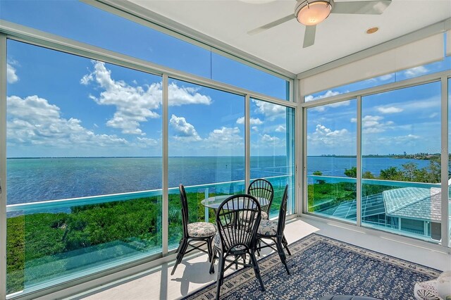 unfurnished sunroom with plenty of natural light, a water view, and ceiling fan