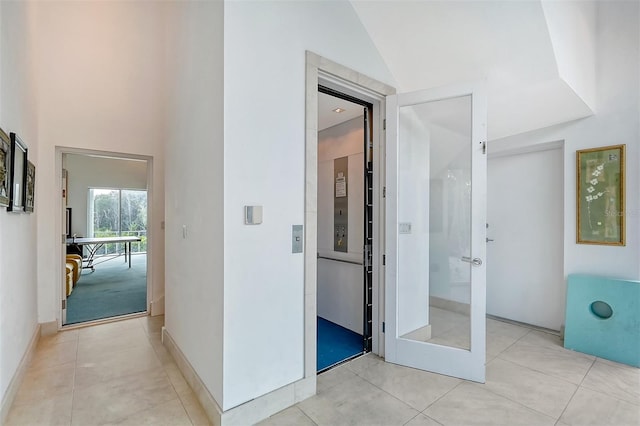 hall with lofted ceiling and light tile patterned floors