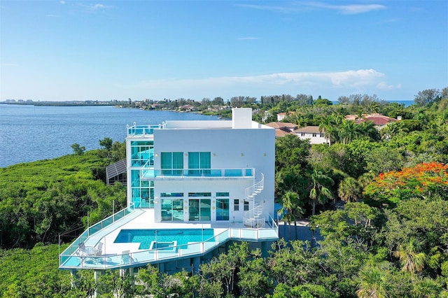 back of property with a balcony, a water view, and a patio area