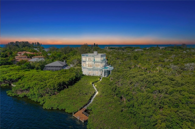 aerial view at dusk featuring a water view