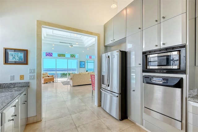 kitchen with light tile patterned floors, stainless steel appliances, white cabinets, and stone counters