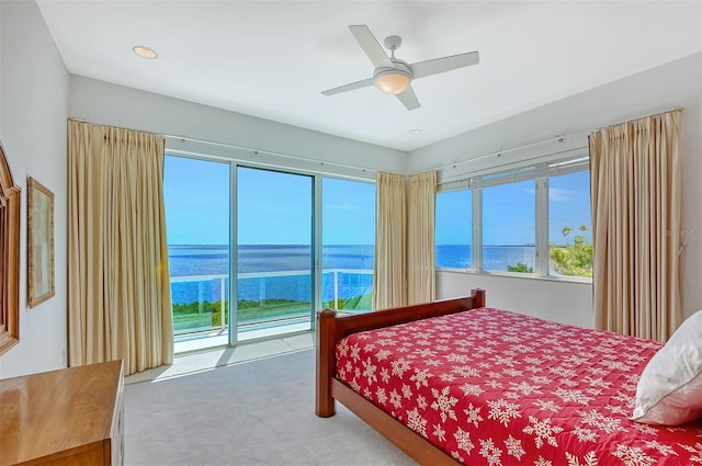 carpeted bedroom with access to exterior, ceiling fan, and a water view