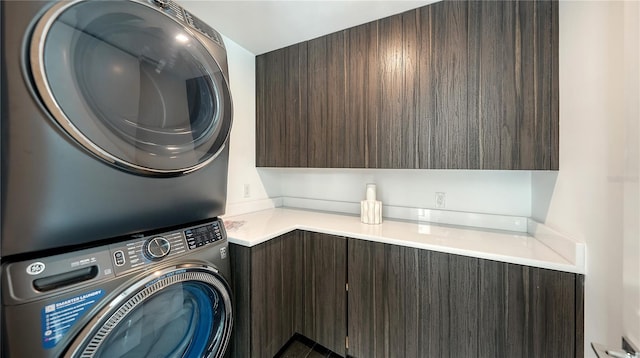 laundry room with stacked washer and dryer and cabinets