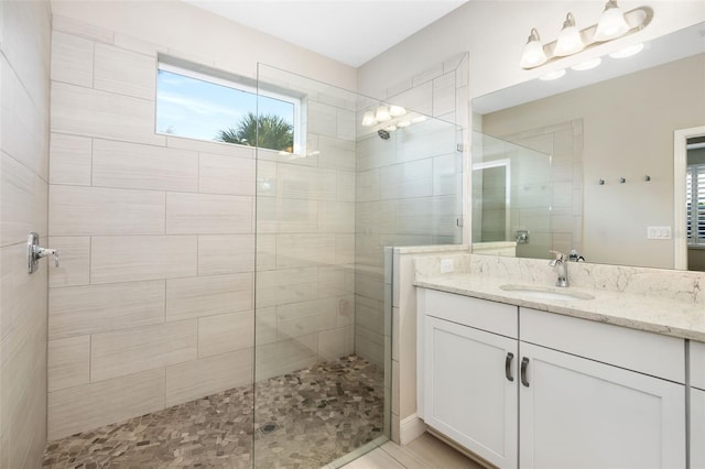 bathroom with tiled shower and vanity