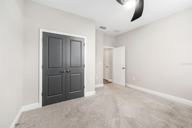 unfurnished bedroom featuring ceiling fan, a closet, and light colored carpet