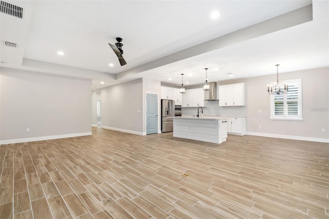 unfurnished living room featuring sink, light hardwood / wood-style flooring, and a notable chandelier